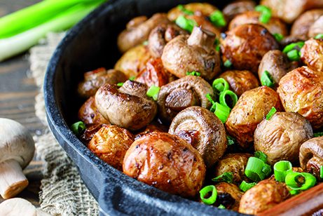 Delicious baked potatoes in cast-iron pan with champignons and g