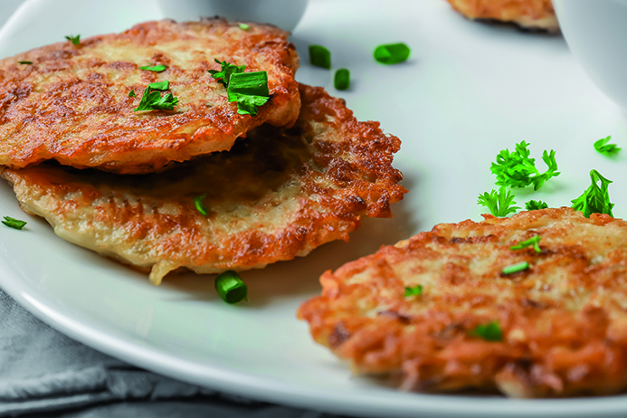 Plate with Hanukkah potato pancakes on table, closeup