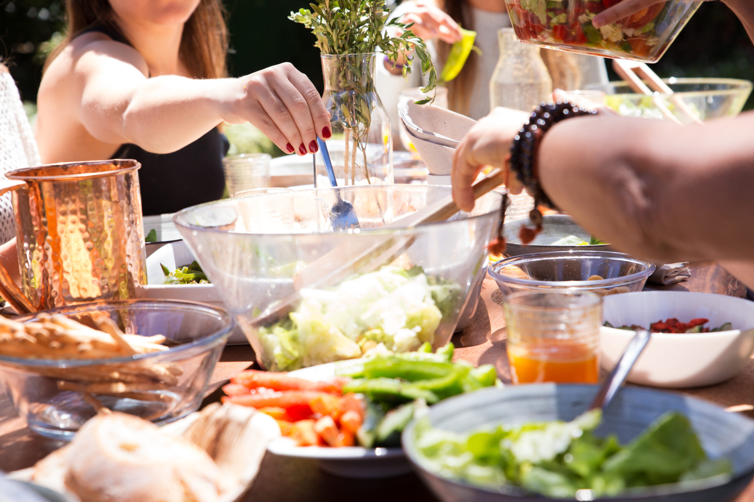 Close-up of bowls and plates with food and female hand with fork